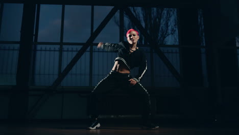 junge frau tanzt hip-hop in einem dunklen studio.