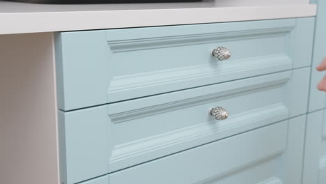 close-up of light blue kitchen drawers being opened