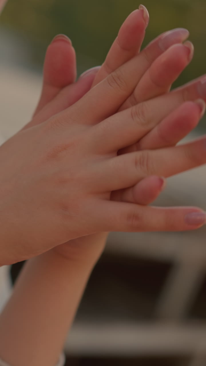 primer plano de una mujer con las manos suavemente unidas, las uñas bien pulidas en foco, expresando un estado de ánimo reflexivo e introspectivo, la luz del sol la ilumina suavemente