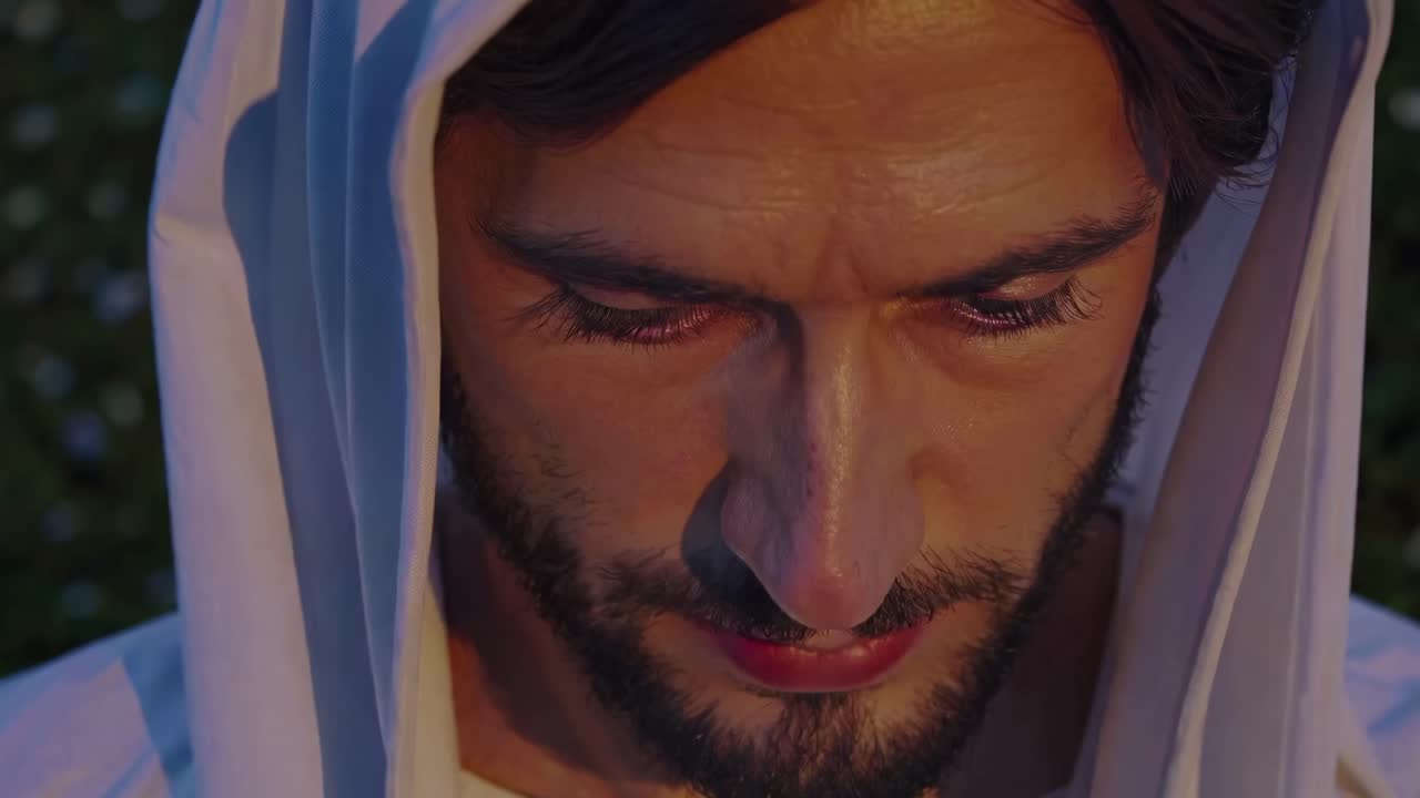 Nahaufnahme eines Videostills von einem nachdenklichen Mann mit Kapuze, der intensive Emotionen einfängt