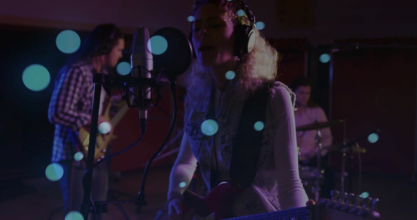 Lead singer starting studio take, singing, strumming while band keeping time under blue bokeh