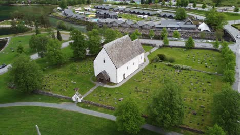 the old church of kinsarvik norway - one of the oldest churches in norway built in year 1160 - rotating aerial view of church exterior and graveyard