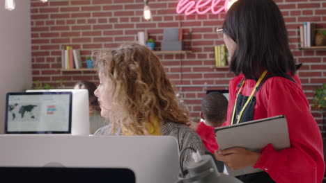 jóvenes empresarios creativos se reúnen líder de equipo asiático mujer señalando a la pantalla compartir ideas lluvia de ideas discutiendo soluciones capacitación pasante usando computadora trabajo en equipo en la oficina moderna