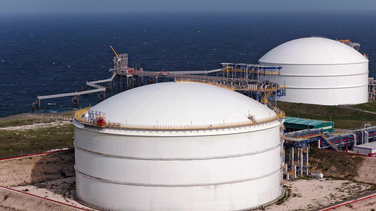 Vista drone di enormi serbatoi di stoccaggio di gas naturale con condutture e infrastrutture marine lungo la costa caraibica presso AES Andres nella Repubblica Dominicana