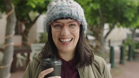 portrait of friendly hipster woman wearing funky glasses smiling cheerful at camera holding coffee beverage enjoying relaxed urban lifestyle