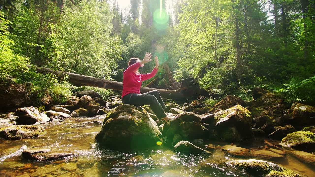 Woman wearing VR headset in a forest beside a stream