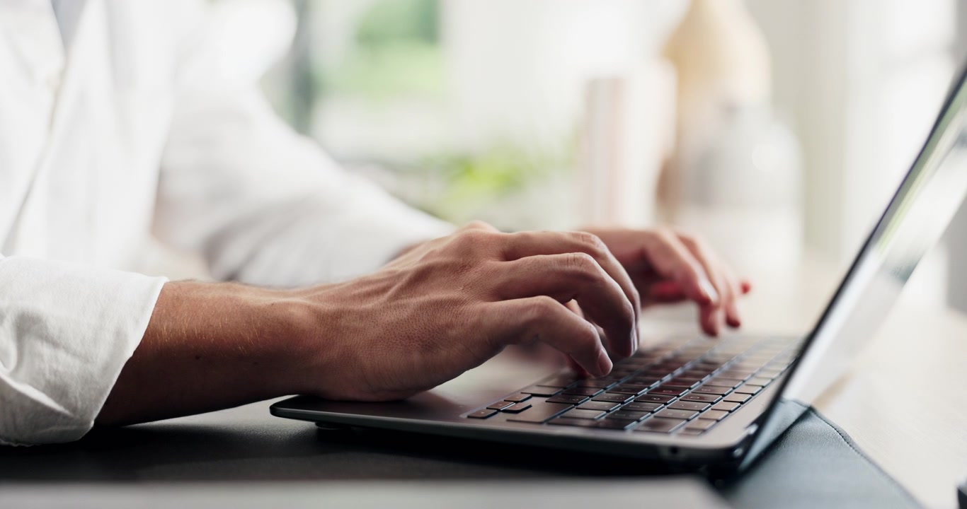 Primo piano di una persona che digita sulla tastiera del laptop in un ufficio luminoso