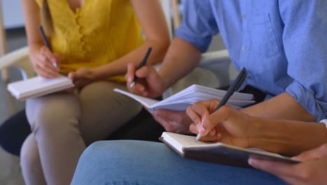 Multi-ethnic-business-colleagues-writing-on-a-diary-in-modern-office-4k