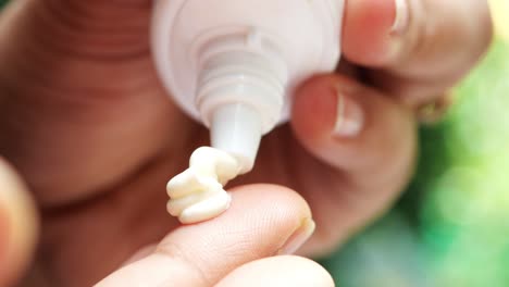 Close-up-of-person-hand-using-sunscreen-cream-outdoor-,