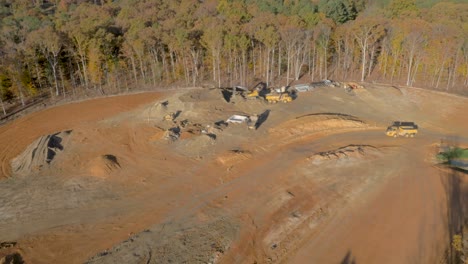 4k-view-of-construction-with-large-yellow-earth-moving-equipment-early-in-the-morning-surrounded-by-trees