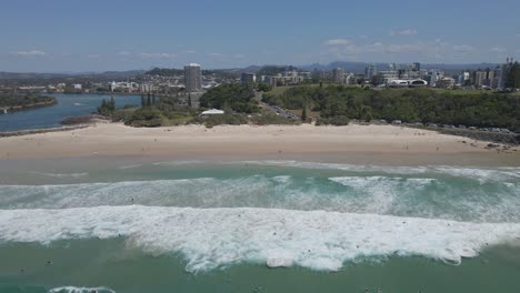 Gente-Caminando-En-La-Playa-De-Arena-Y-Surfistas-Disfrutando-De-Las-Olas-Del-Océano-En-Letitia-Beach-En-Gold-Coast,-Australia