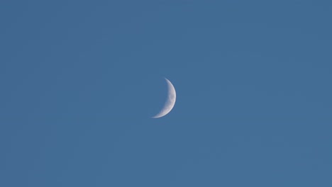 wide shot of the skies with a pale waxing crescent moon