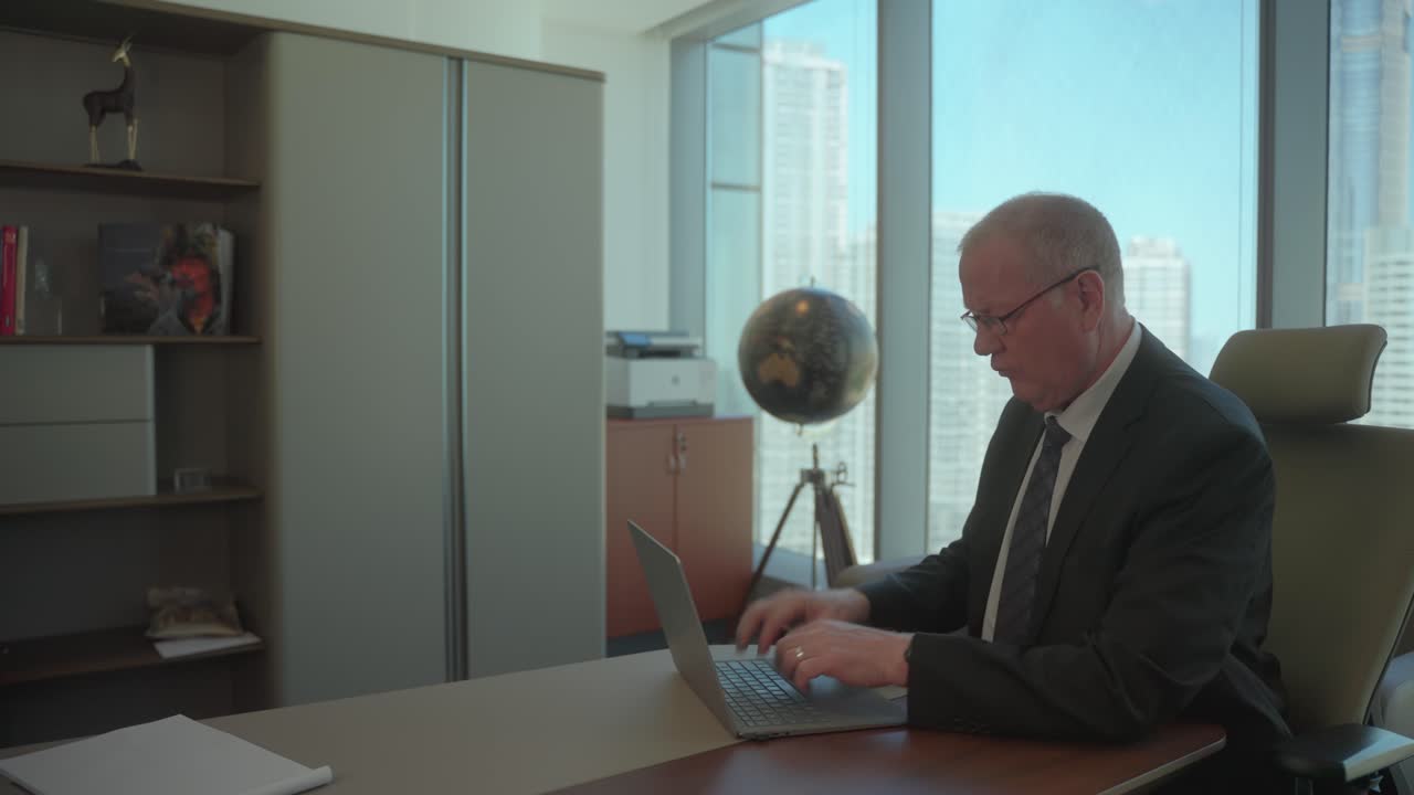 Senior executive businessman in an office on his laptop makes an important decision - slow motion