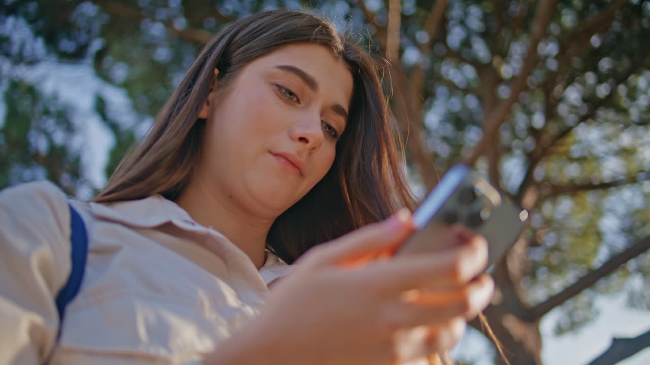 아름다운 빛의 자연에서 드폰으로 메시지를 읽는 진지한 소녀.