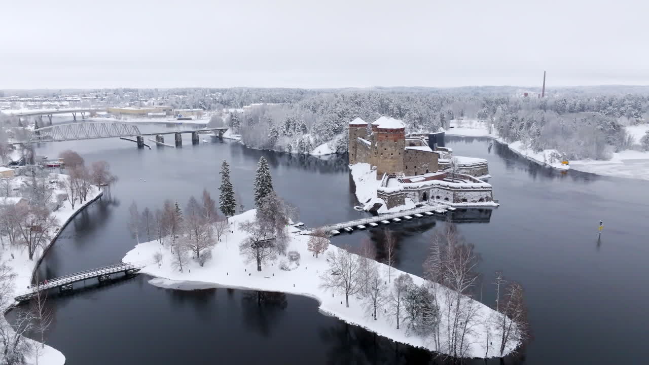AERIAL: Olavinlinna castle, Tallisaari island and frozen lake Saimaa, winter day