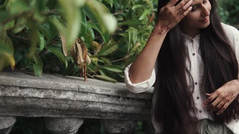 mujer con tatuajes de henna en un jardín