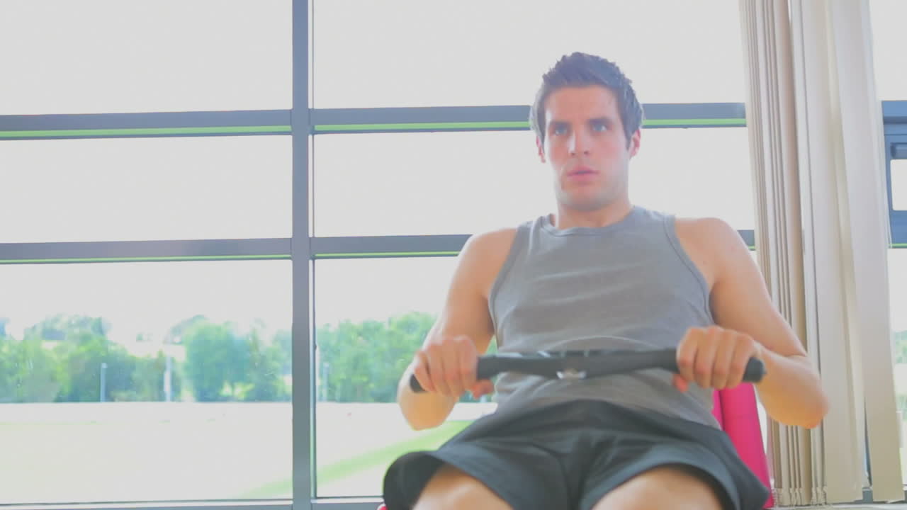 집중된 남자가 기계에서 rowing의 비디오