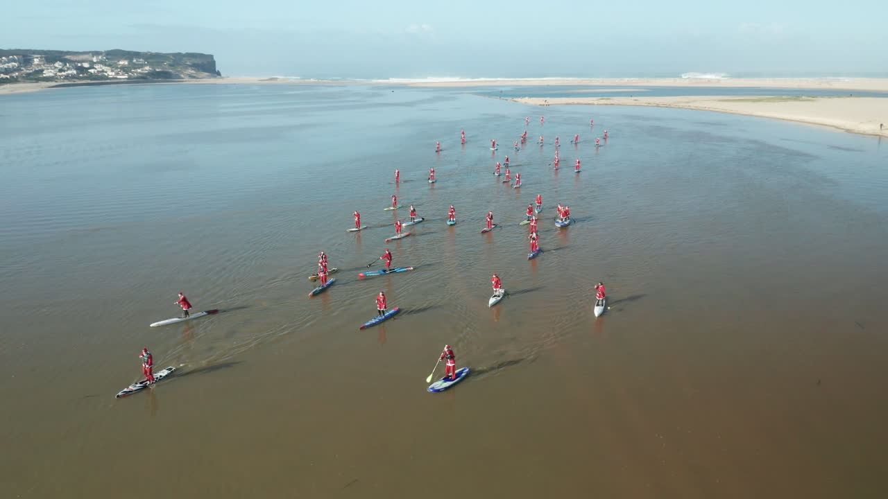 포르투갈 오비두스 석호에서 산타클로스 옷을 입은 패들 보드에 있는 사람들과 함께 고요한 바다의 탁 트인 전망