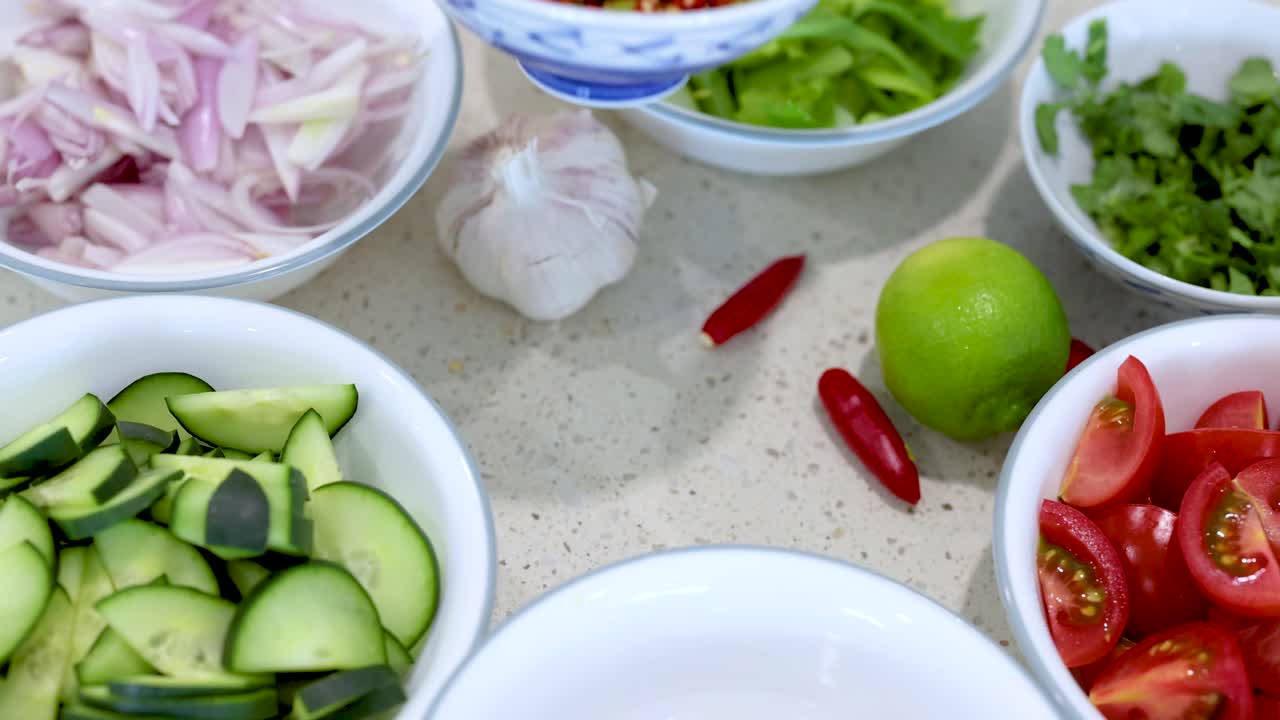 A vibrant assortment of fresh vegetables and spices arranged on a countertop, highlighting a hand reaching for a lime
