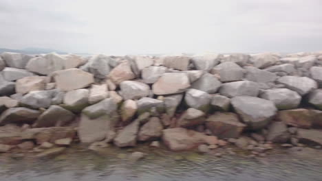 flying along a rocky seawall in southern california on an overcast afternoon