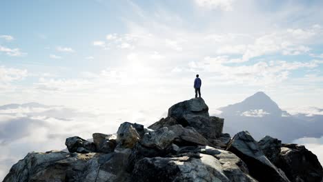 adventurous male hiker standing on rocky cliff surrounded by mountains