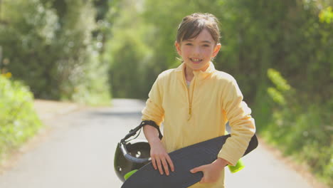 Porträt-Eines-Mädchens-Mit-Skateboard,-Das-Die-Landstraße-Entlang-Läuft