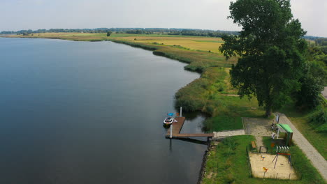 aerial view of small dock near the river with fields in the background