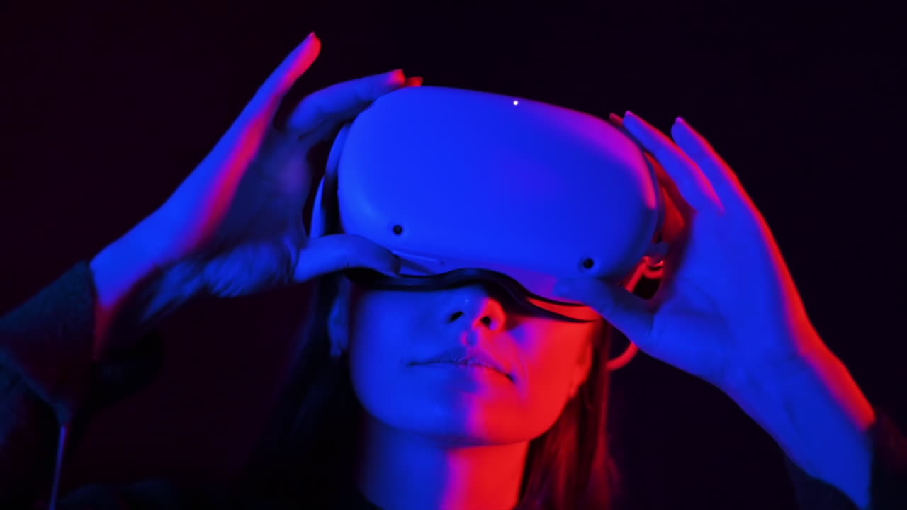A young woman is excited while wearing VR glasses, Red and blue illumination. Slow motion