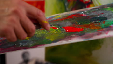 handheld shot of man hand selecting paint on board, close up
