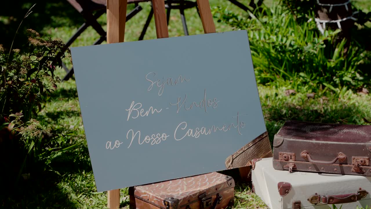 Elegant welcome sign for a wedding displayed outdoors with vintage suitcases nearby