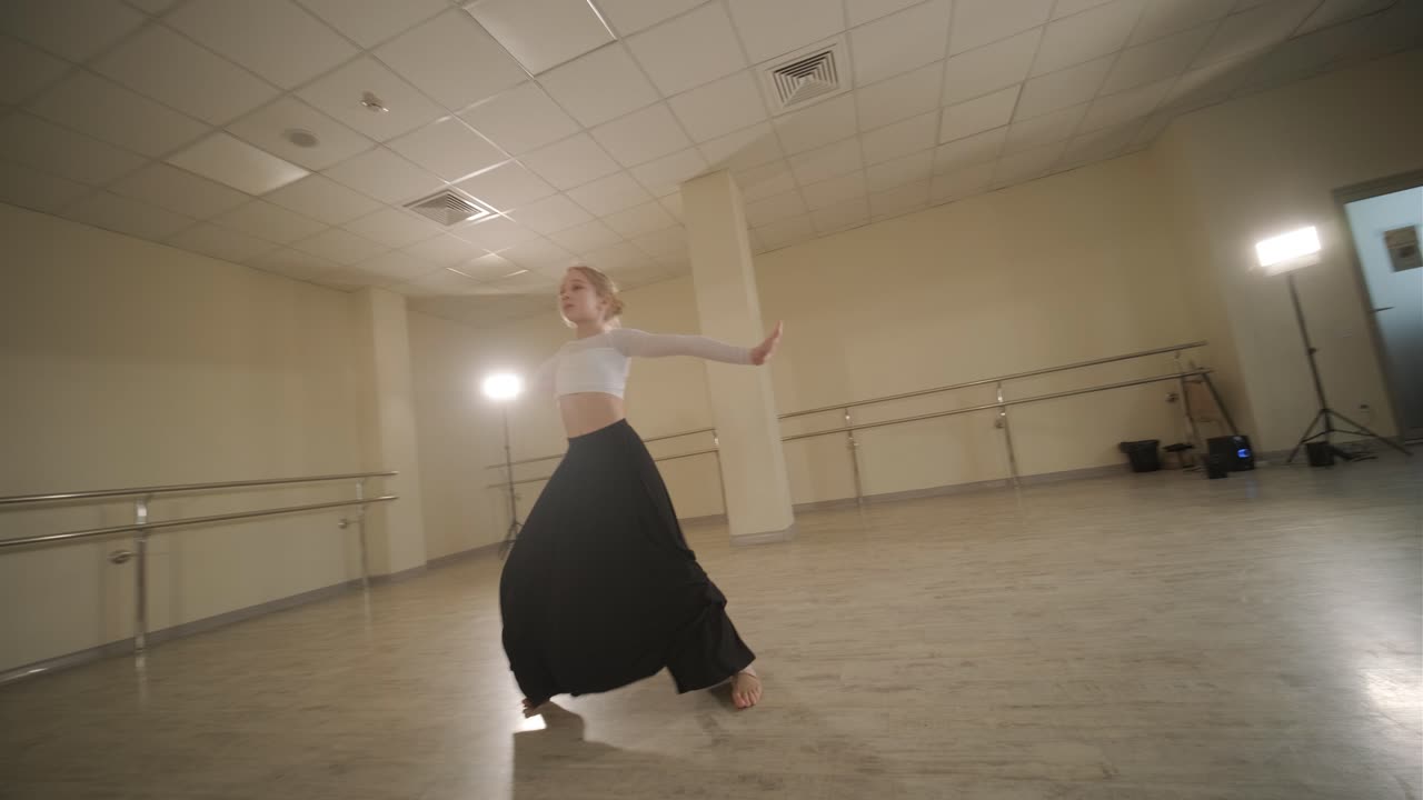 un grupo de jóvenes estudiantes de ballet con ropa de baile negra practicando posiciones en un amplio estudio de ballet con pisos de madera y barras montadas en la pared. expresiones enfocadas y movimientos sincronizados.