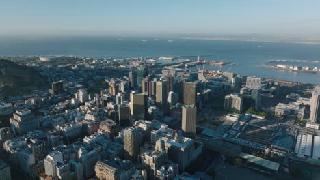Aerial-panoramic-footage-of-city-and-naval-harbour-in-sea-bay.-Tall-office-buildings-in-city-centre.-Cape-Town,-South-Africa