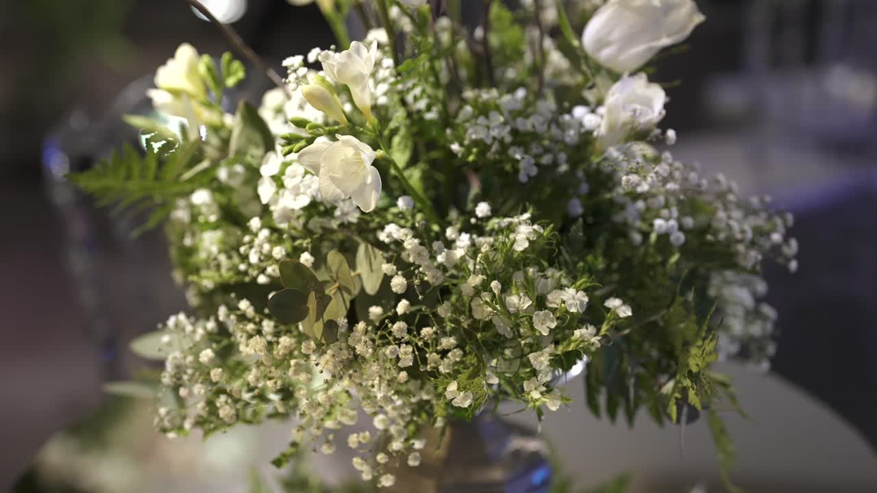 Slow push-in close-up on white freesia and gypsophila bouquet with soft lighting