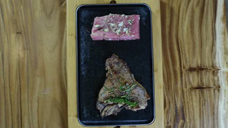 a slice of grilled steak and fresh salmon with herbs and spices with two dips on the side - top view shot