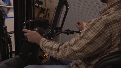 close up of blue collar worker operating the levers of an electric forklift