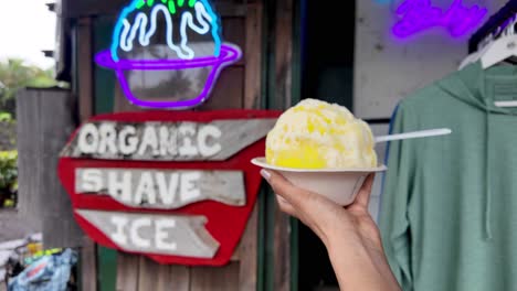 shave ice - hawaiian shaved ice dessert. close up of traditional local dessert food, hawaii. hawaii woman on hanalei beach holding hawaiian shave ice in a hand, a local shaved ice dessert.