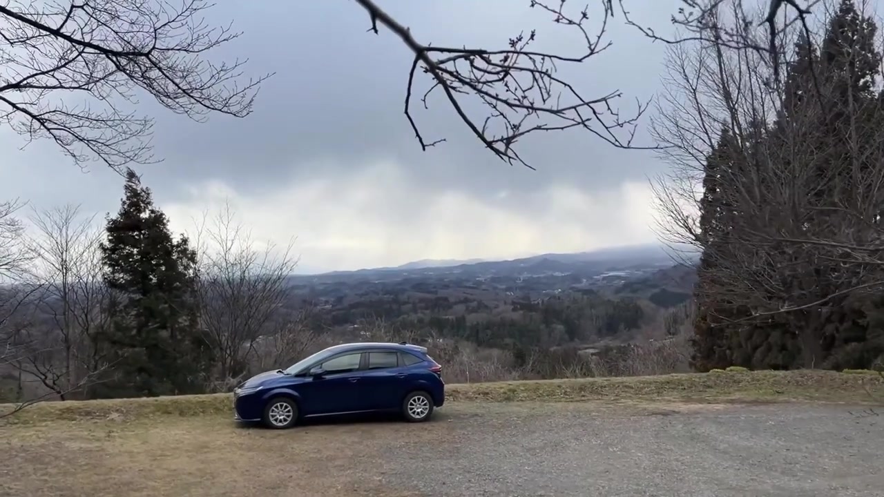 Auto blu parcheggiata sul bordo di una strada di montagna.
