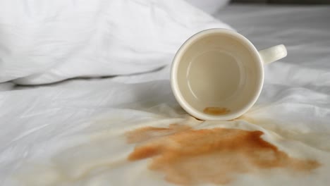 Cup-of-coffee-spilled-on-white-bed