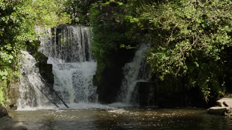 Zeitlupen-Wasserfall-Mit-Bäumen-Und-Felsen-An-Einem-Sonnigen-Tag-In-Swansea,-Großbritannien