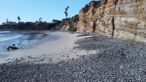 flying-low-to-the-ground-over-rocks-and-by-a-cliff-with-houses-on-top