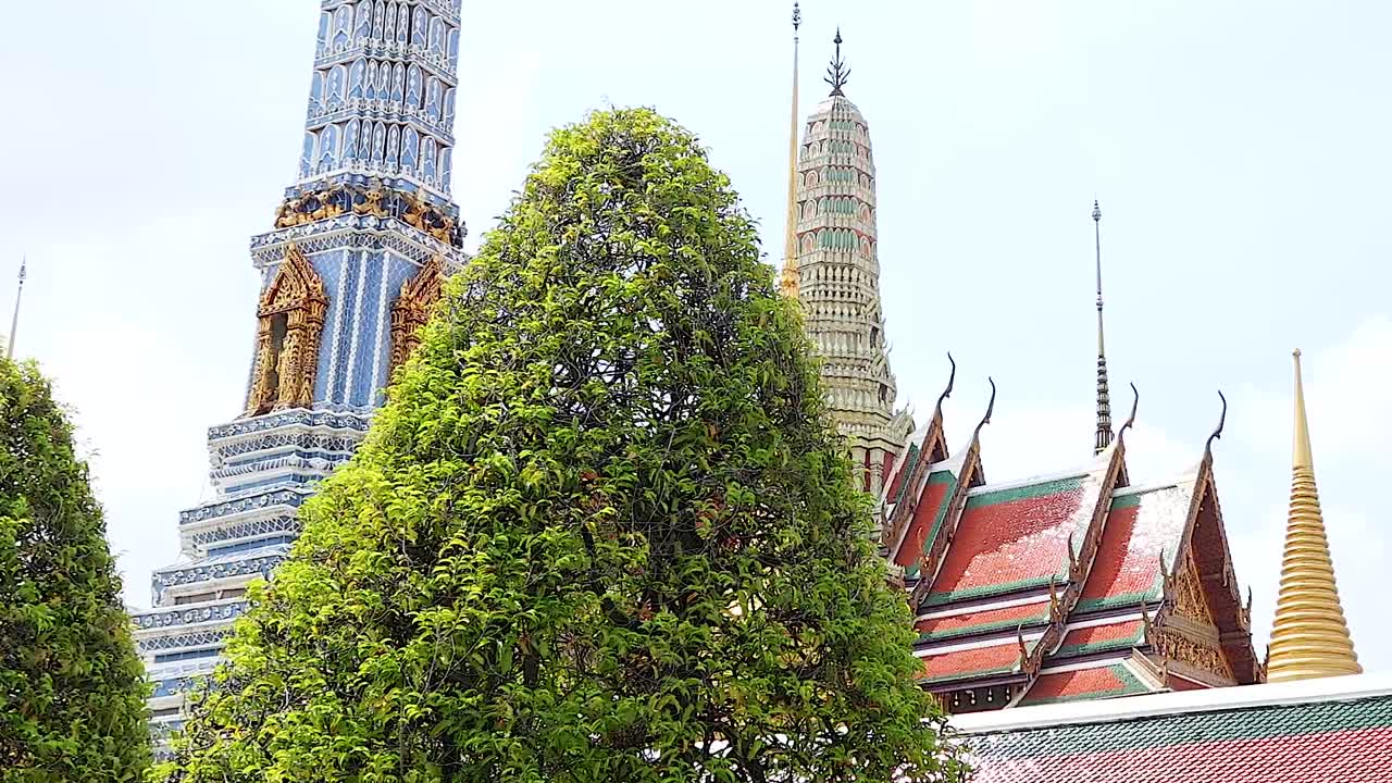 A vibrant scene featuring temple spires and lush trees under a clear blue sky.
