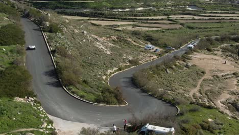 white race car drifting on the curved road track on a sunny day - aerial shot