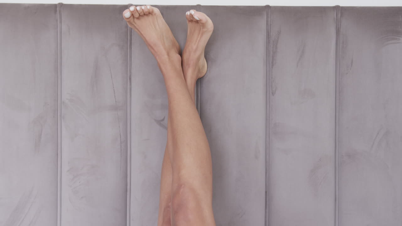 집에서 침대에 누워있는 두 인종 여성의 다리의 근접, 느린 동작