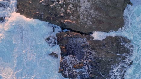 Imágenes-De-Arriba-Hacia-Abajo-Del-Dron-De-La-Jolla-Cove-Desde-Las-Rocas-Iluminadas-Por-El-Amanecer-Hasta-El-Océano-Mientras-Las-Olas-Rompen