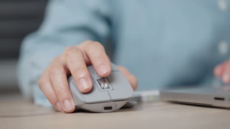 close-up hand of a businessman using wireless or bluetooth mouse. scrolling the wheel working with a pc or laptop.