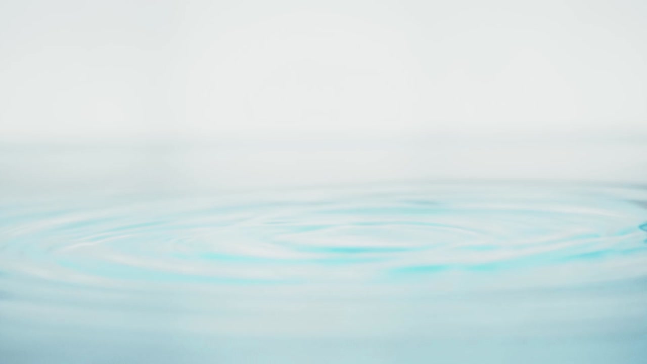 슬로우 모션의 깨끗한 물 표면은 물이 튀는 상점으로 화면을 채우고 기포로 액체 표면을 흔들고 있습니다.