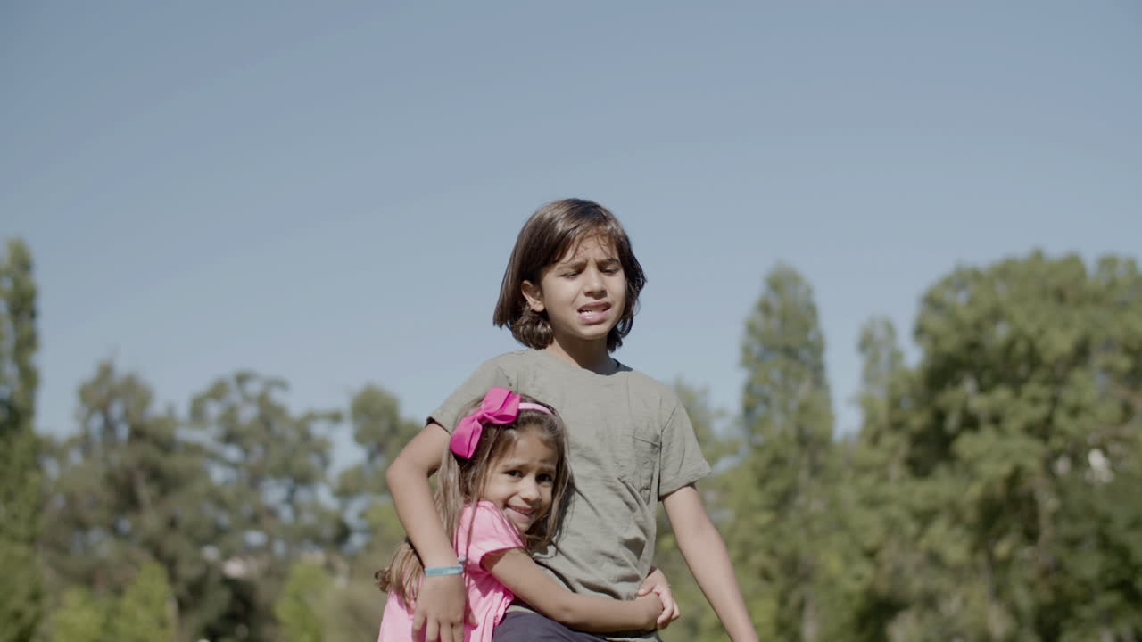 Plano medio de una hermana asustada abrazando a su hermano en un parque de verano
