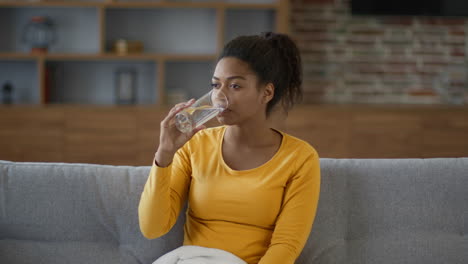 woman drinking water on couch