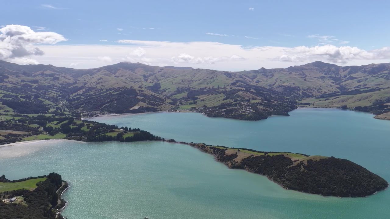 Volo di drone sopra il porto di Akaroa e la costa della penisola di Banks nell'Isola del Sud della Nuova Zelanda, veduta naturalistica e paesaggistica.