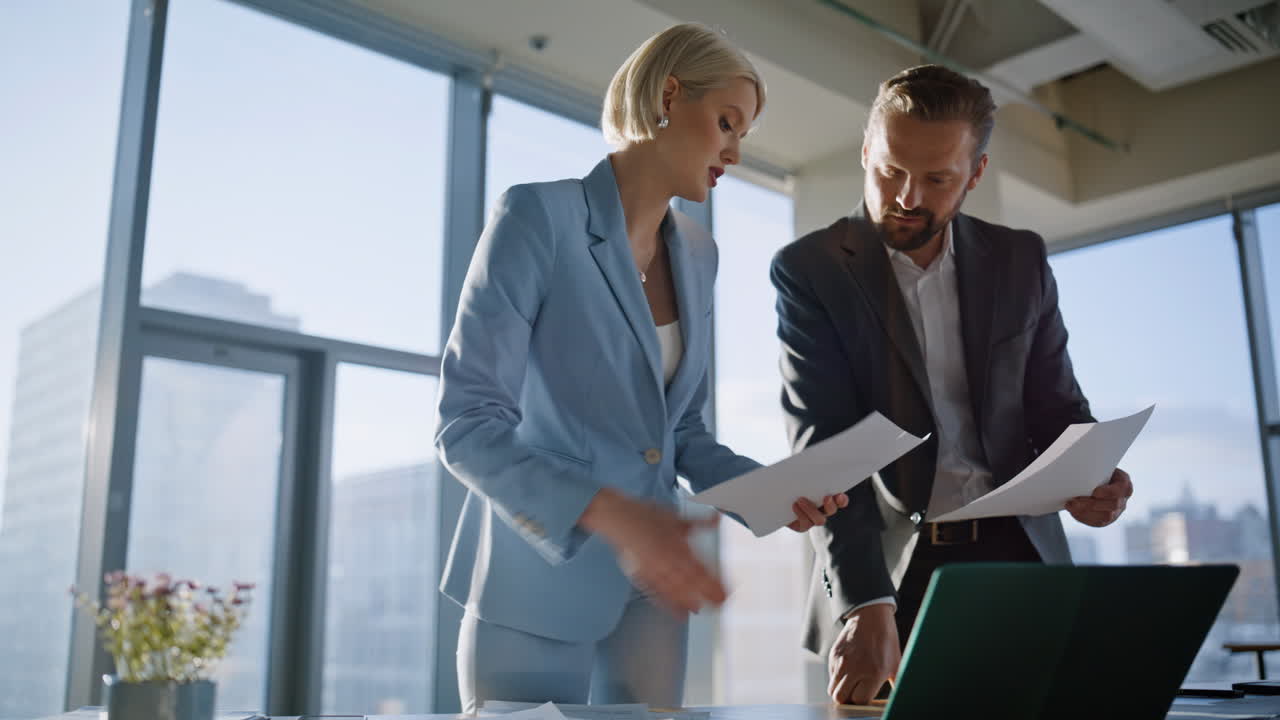 Legal professionals examining papers sunny office. Partners reviewing contract